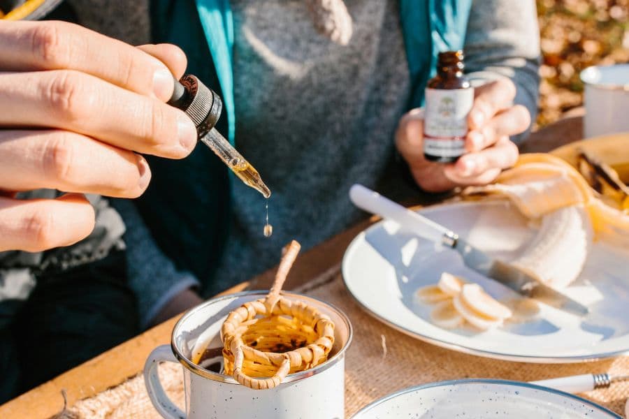 Person adds liquid supplement to tea using a dropper