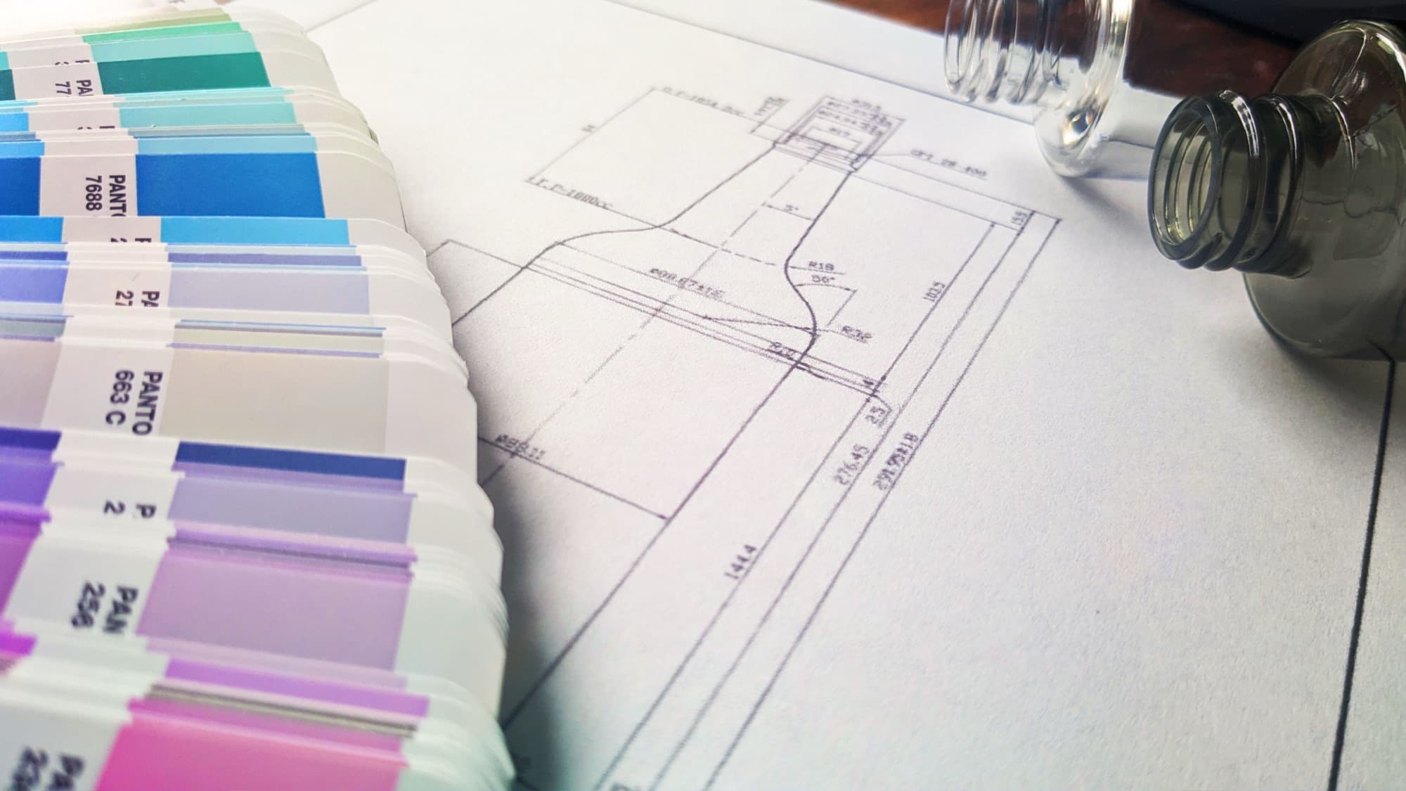 Pantone color swatches laid over a bottle design blueprint
